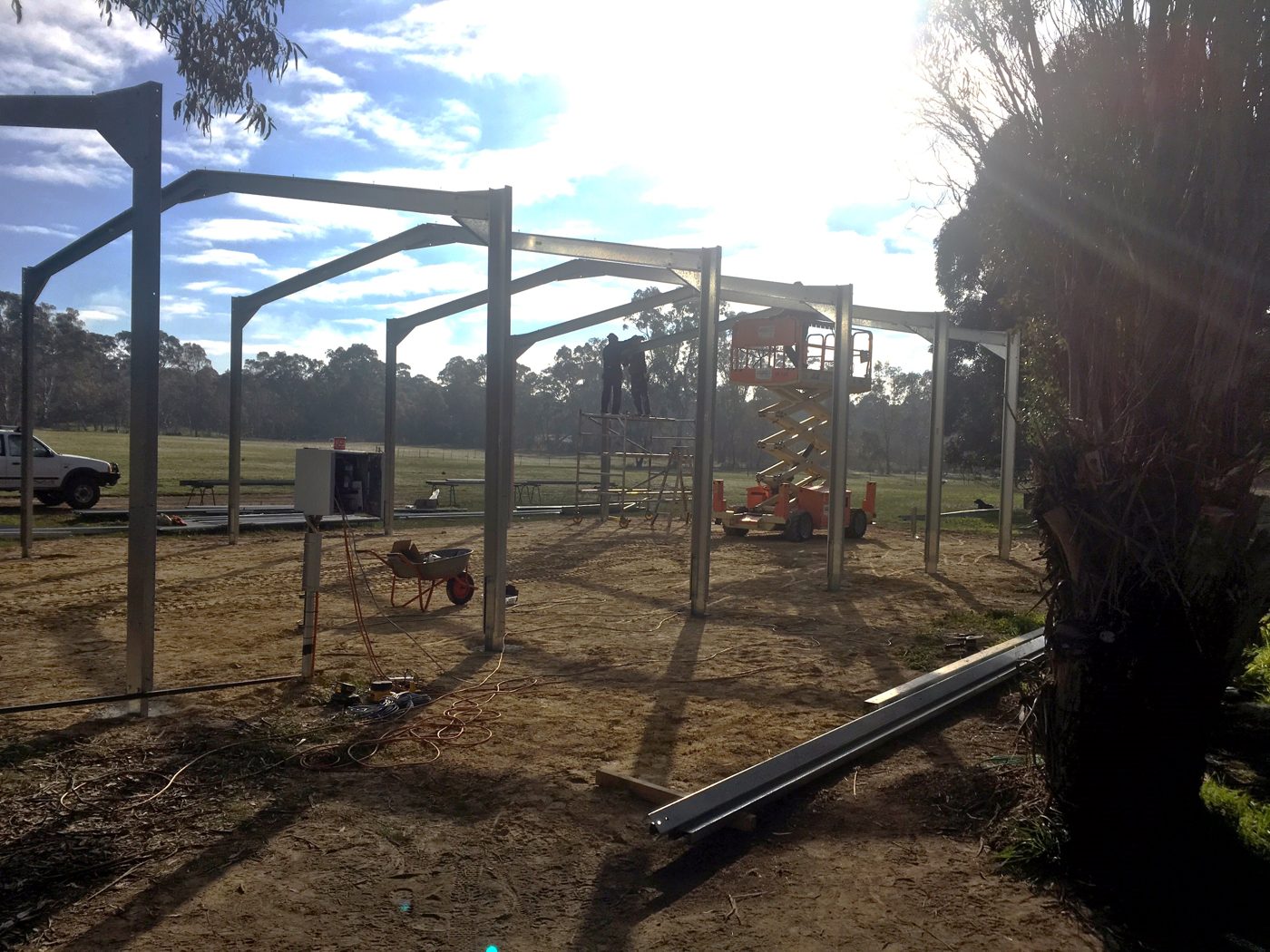 Shed City bolted portal frames standing on site while workers fit the rafters